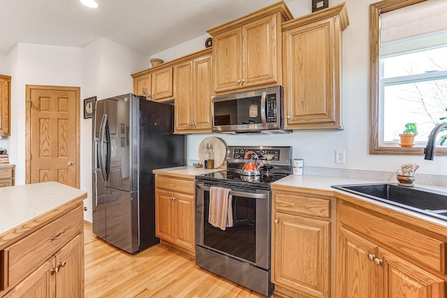 1103 Park Ln SE, New Prague, MN 56071 - kitchen featuring stainless steel appliances, a sink, light wood-style floors, light countertops, and a textured ceiling