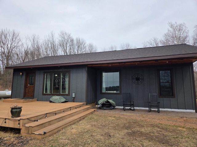 rear view of house featuring board and batten siding, a shingled roof, and a deck