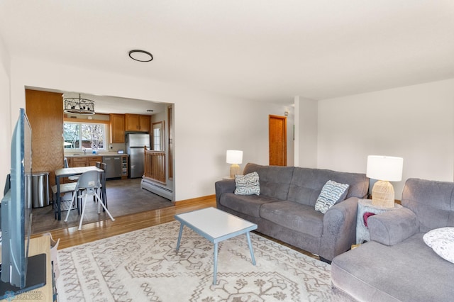 living area with wood finished floors, a baseboard radiator, and baseboards