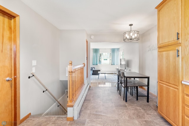 hallway with an upstairs landing, a chandelier, and baseboards