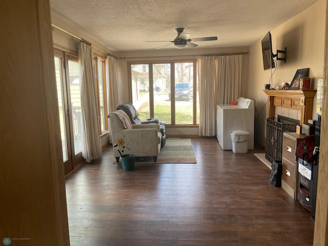 101 Oak St, Lisbon, ND 58054 - living area featuring washer / dryer, a textured ceiling, a ceiling fan, dark wood-style flooring, and a fireplace