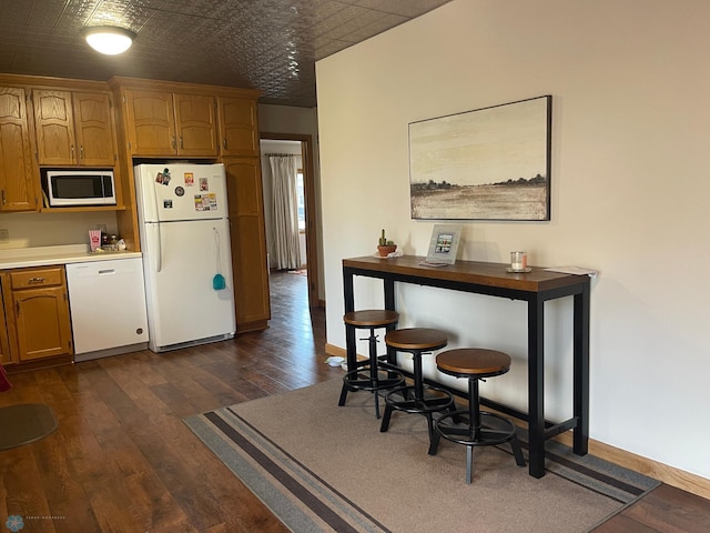 101 Oak St, Lisbon, ND 58054 - kitchen featuring white appliances, dark wood-style floors, baseboards, brown cabinets, and an ornate ceiling