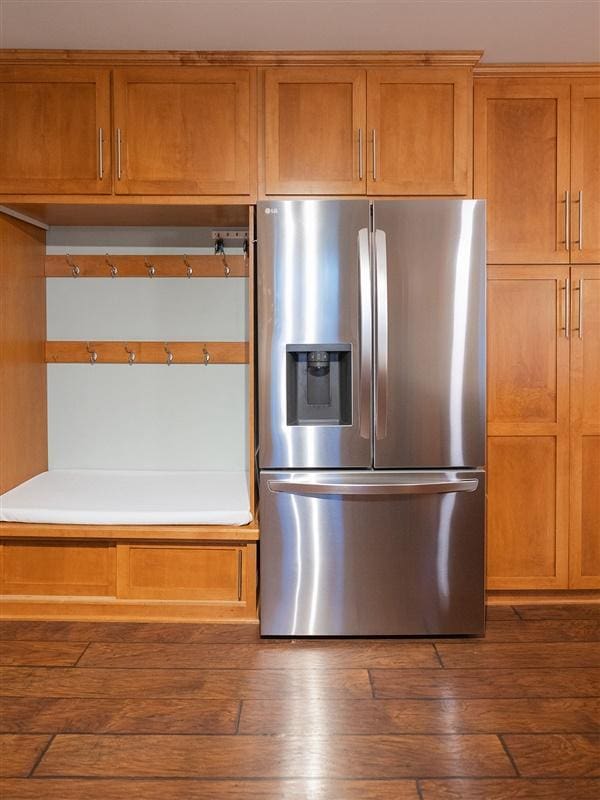 kitchen featuring brown cabinetry, dark wood-style floors, and stainless steel refrigerator with ice dispenser
