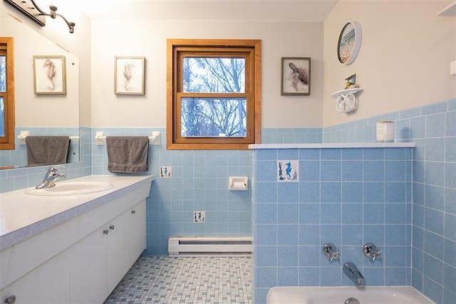 bathroom with a wainscoted wall, a baseboard radiator, tile walls, a washtub, and vanity