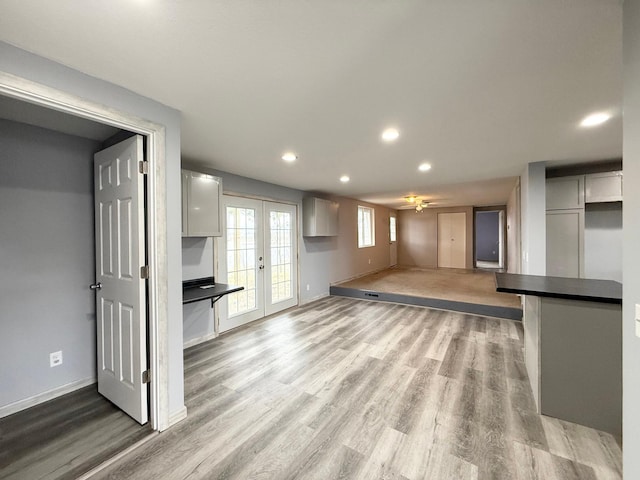 unfurnished living room with a ceiling fan, french doors, recessed lighting, baseboards, and light wood finished floors