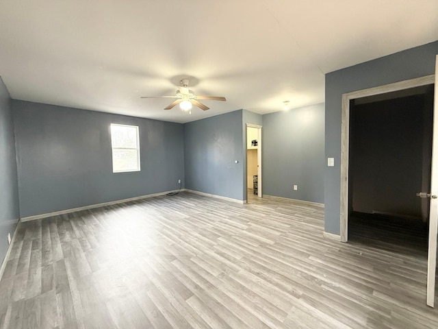 spare room featuring baseboards, light wood-style flooring, and ceiling fan