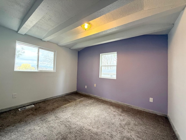 carpeted spare room with visible vents, baseboards, and beamed ceiling