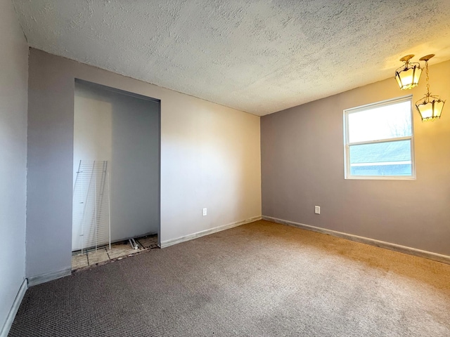 carpeted empty room with a textured ceiling and baseboards
