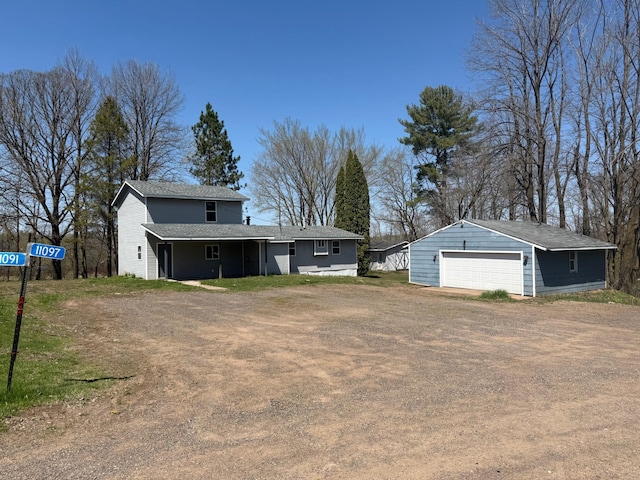 view of front of property featuring an outdoor structure, a shingled roof, and a garage