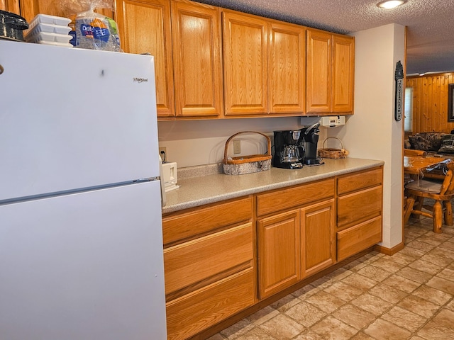 44948 Plentywood Rd, Perham, MN 56573 - kitchen featuring freestanding refrigerator, light countertops, a textured ceiling, and brown cabinets