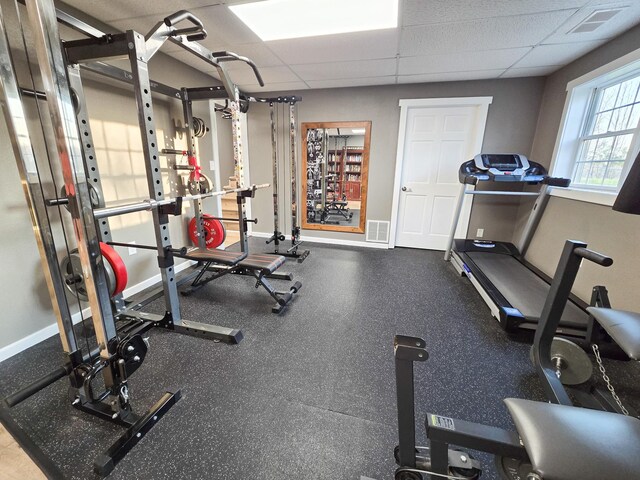 exercise room featuring baseboards and a drop ceiling