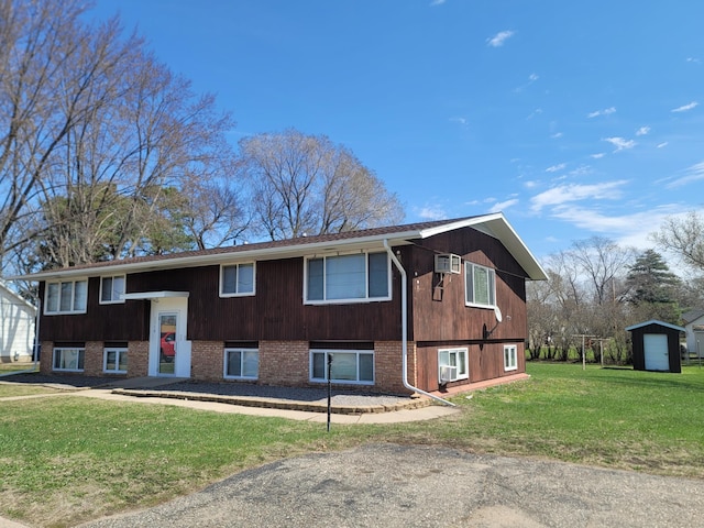 view of front of property with a front yard, a shed, brick siding, and an outdoor structure