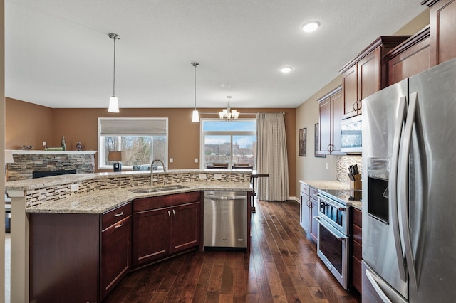 kitchen featuring stainless steel appliances, a sink, tasteful backsplash, dark wood-style flooring, and a chandelier