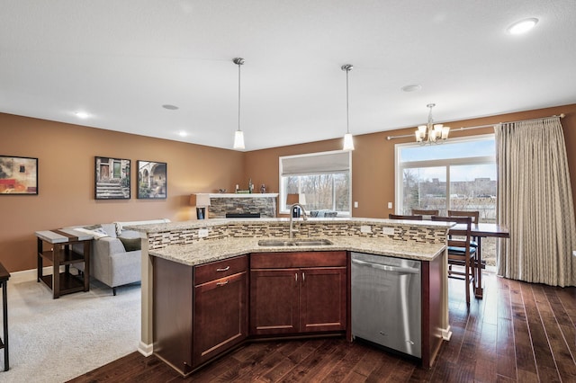 kitchen with stainless steel dishwasher, a sink, a fireplace, a chandelier, and dark wood finished floors