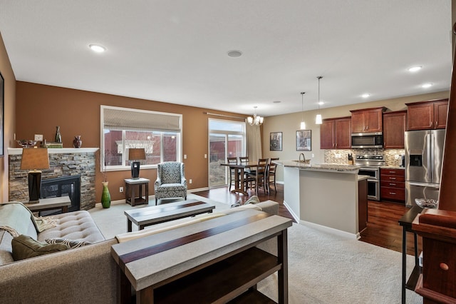 living area featuring dark colored carpet, a chandelier, a fireplace, baseboards, and recessed lighting