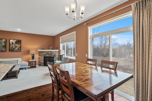dining space featuring dark wood-type flooring, a chandelier, a fireplace, and recessed lighting
