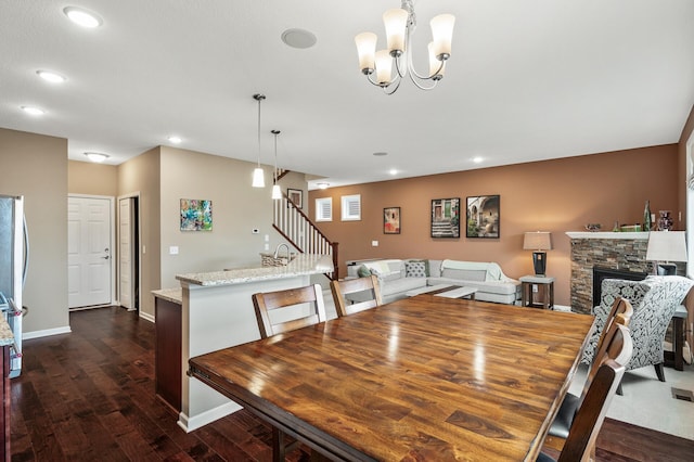 dining space with stairs, dark wood-type flooring, recessed lighting, a stone fireplace, and baseboards