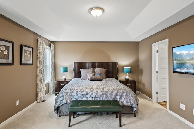 bedroom featuring a tray ceiling, carpet, and baseboards