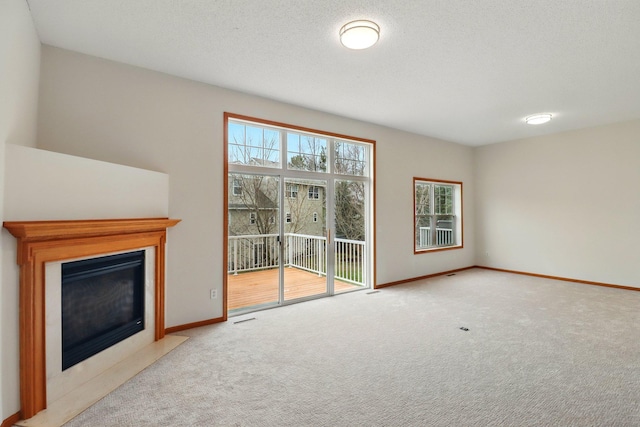 unfurnished living room featuring baseboards, visible vents, a fireplace with flush hearth, and carpet