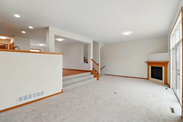 unfurnished living room with light colored carpet, baseboards, and visible vents