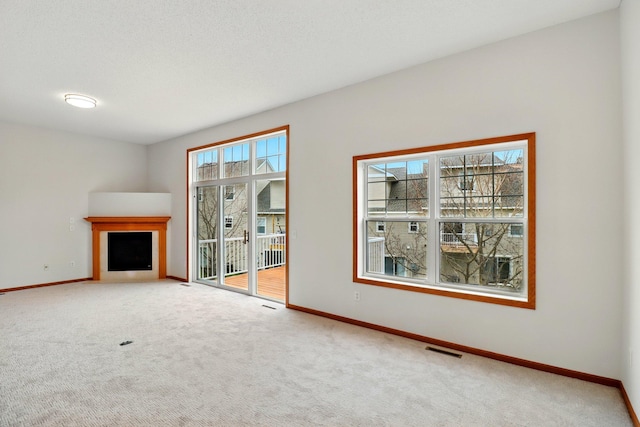 unfurnished living room featuring baseboards, carpet flooring, a fireplace, and visible vents