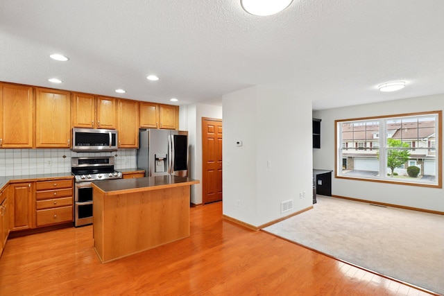 kitchen with light wood-type flooring, baseboards, visible vents, and appliances with stainless steel finishes