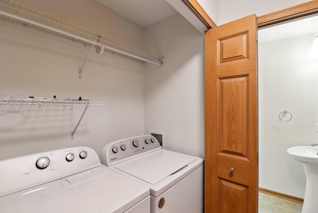 laundry room with laundry area, washer and clothes dryer, baseboards, and light tile patterned floors