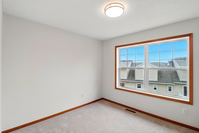 spare room with light colored carpet, visible vents, and baseboards