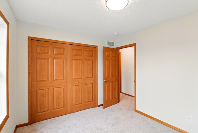 unfurnished bedroom featuring light carpet, a closet, baseboards, and visible vents