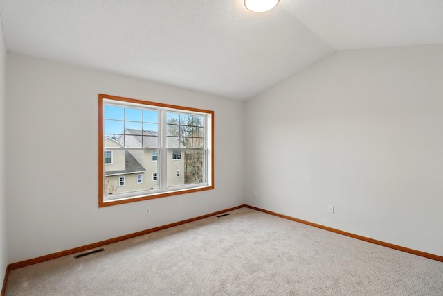 unfurnished room featuring lofted ceiling, baseboards, visible vents, and carpet