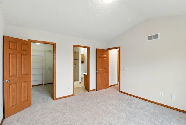 unfurnished bedroom with a spacious closet, a closet, visible vents, and light colored carpet