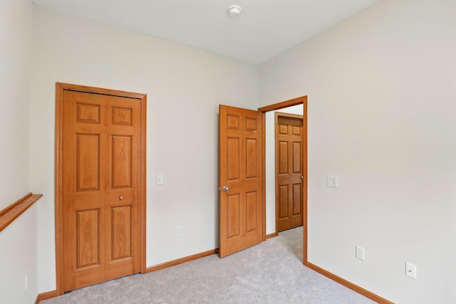 unfurnished bedroom featuring light carpet and baseboards
