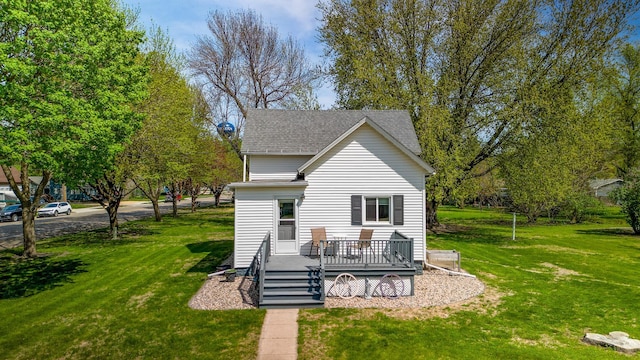back of house featuring a wooden deck, a lawn, and a shingled roof