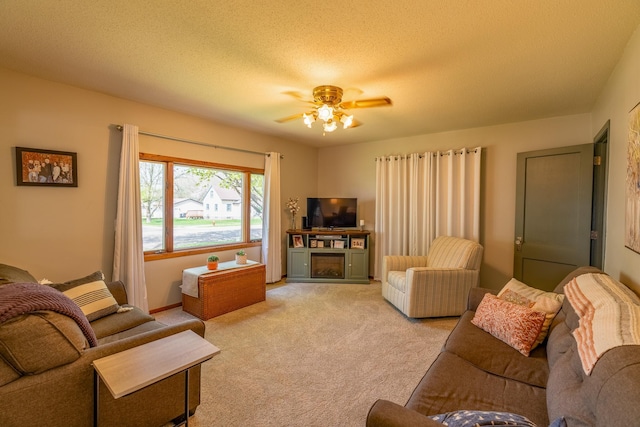living room with light carpet, a ceiling fan, and a textured ceiling