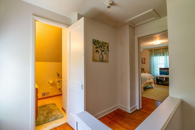 hall with attic access, wood finished floors, and baseboards