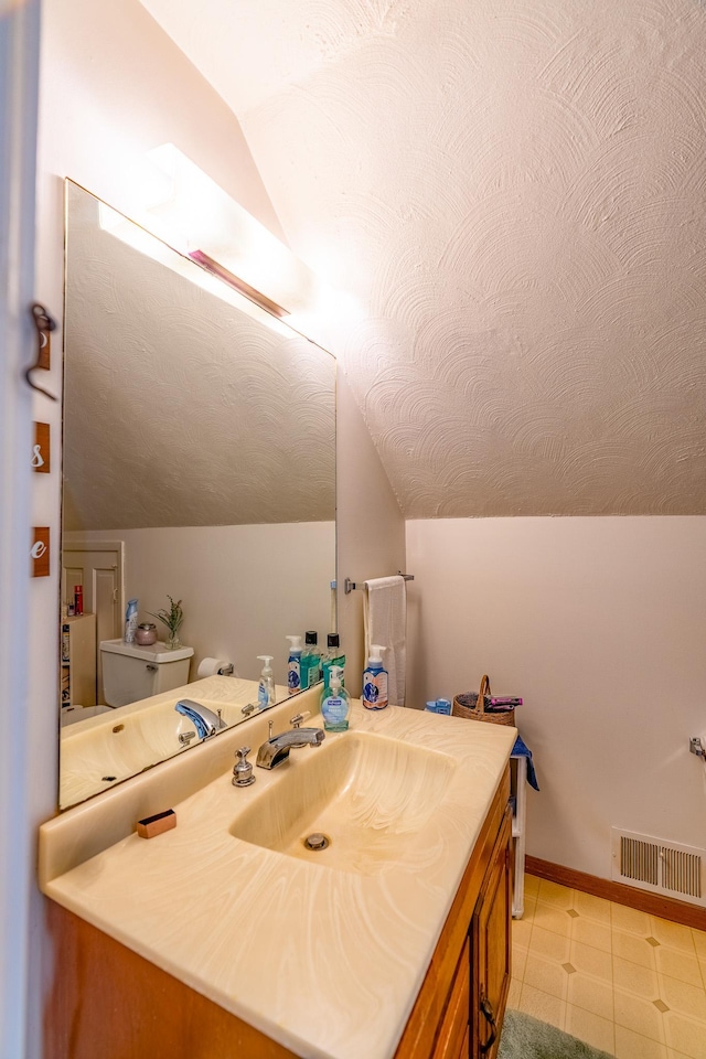 bathroom with lofted ceiling, toilet, and vanity