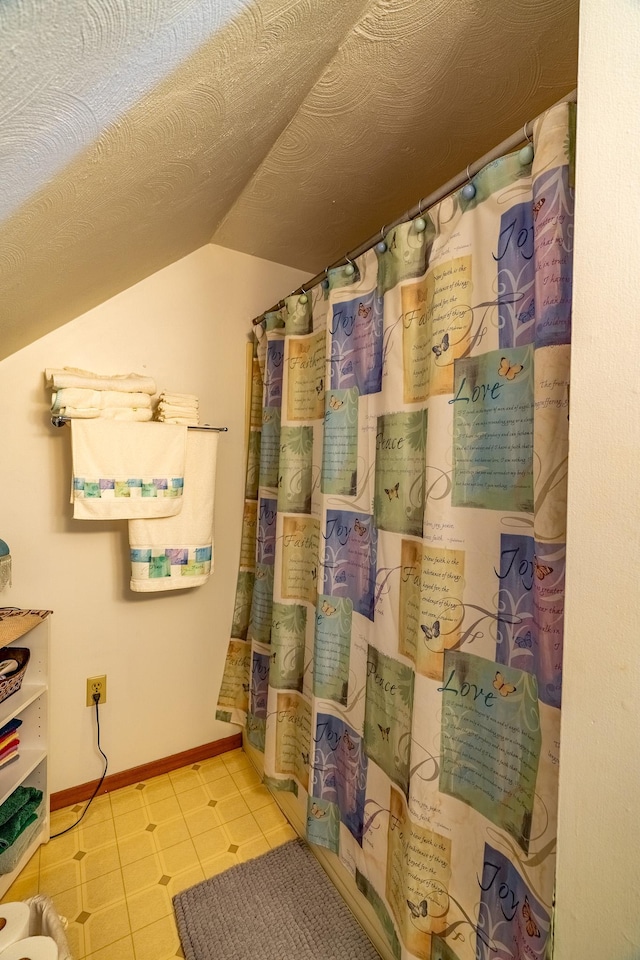 full bath featuring lofted ceiling, baseboards, a shower with shower curtain, and tile patterned flooring