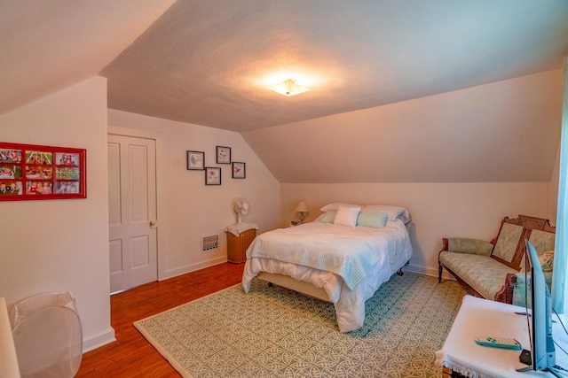 bedroom featuring lofted ceiling, light wood-type flooring, and baseboards