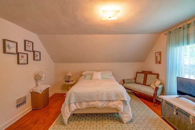 bedroom featuring vaulted ceiling, baseboards, and wood finished floors