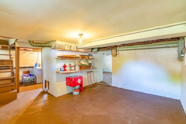 unfinished below grade area with washer / clothes dryer, concrete block wall, and electric panel