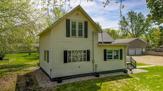 back of house featuring a detached garage and a shingled roof
