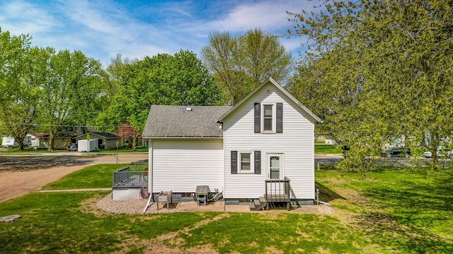 back of house featuring a shingled roof, a yard, and entry steps