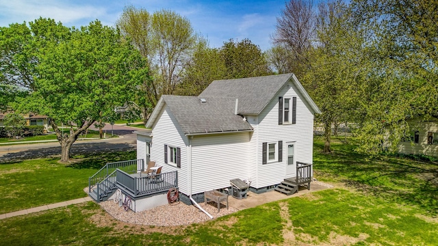 back of house featuring roof with shingles, a yard, and a deck