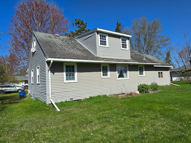 rear view of property featuring a yard and roof with shingles