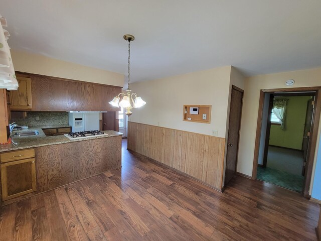 kitchen featuring dark wood finished floors, wainscoting, a sink, brown cabinets, and white gas cooktop
