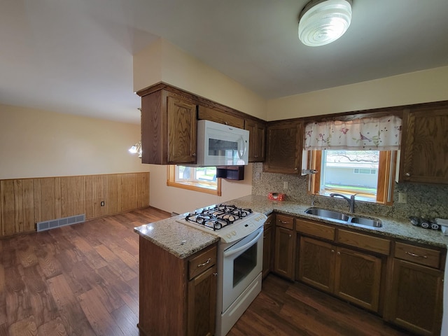kitchen with white appliances, a sink, tasteful backsplash, and dark wood-style flooring
