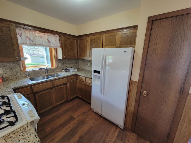 kitchen featuring white appliances, a sink, dark wood finished floors, and backsplash