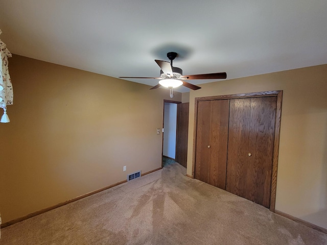 unfurnished bedroom featuring light colored carpet, a closet, a ceiling fan, and baseboards
