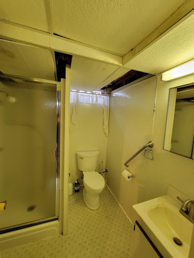 bathroom with a stall shower, toilet, vanity, and tile patterned floors