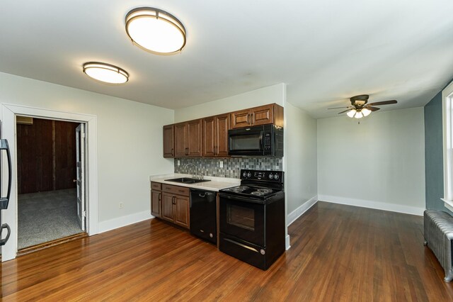 kitchen featuring black appliances, a sink, radiator, and baseboards
